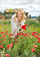 Beautiful young female  in white dress holding bouquet of  poppy  flowers