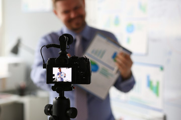 Male in suit and tie show stats graph pad making promo videoblog or photo session in office camcorder to tripod closeup. Vlogger selfie sale solution or finance advisor management information © H_Ko