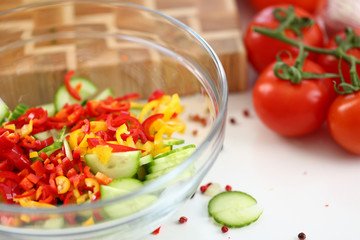 Raw Healthy Chopped Vegetable Salad Ingredient. Bowl with Slices of Chili Pepper and Small Pieces of Green Cucumber. Red Tomato at Kitchen Worktop. Healthy Dieting Dish Horizontal Photography