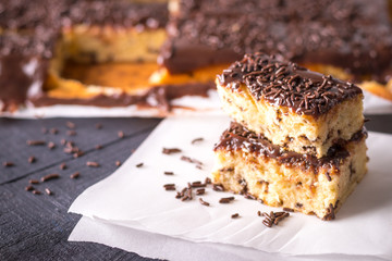 Pedaços de Bolo Formigueiro com Cobertura de Chocolate ao Leite e Granulado de Brigadeiro sobre papel manteiga