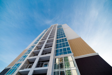 part of a tall building with panoramic Windows and balconies against the blue sky