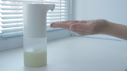 Girl using automatic foam soap dispenser, washing hands, close, macro, on the windowsill, right hand