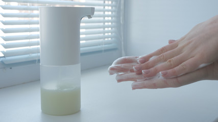 Girl using automatic foam soap dispenser, washing hands, close, macro, on the windowsill, right hand