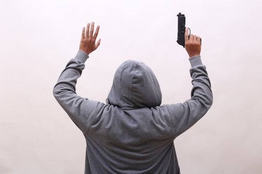 rear view of man holding gun with both hands raised