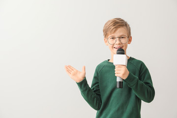 Little journalist with microphone on white background