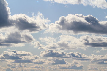 Fototapeta premium Clouds in the blue sky at sunset or dawn backlit by the sun. Place for text and design.