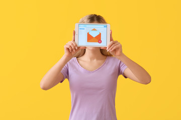 Young woman with tablet computer checking her e-mail on color background
