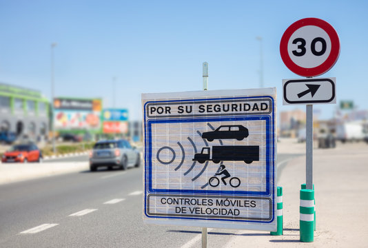 A rectangular sign on a Spanish street warns of a speed control. A round sign allows speed 30. Translation of the text - Speed control for your safety.