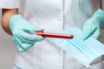 medical doctor nurse woman wearing latex gloves - holding virus blood test and protective mask