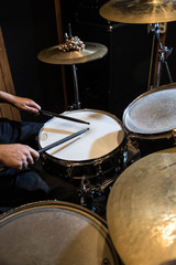 
Professional drum set closeup. Man drummer with drumsticks playing drums and cymbals, on the live music rock concert or in recording studio   
