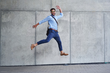Obraz na płótnie Canvas Joyful young businessman jumping up and looking at camera