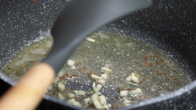 Frying Onions with green chilies, garlic, ginger and cumin seeds to make Tadka to make of spicy Indian lentils called Daal tadka. A 4K video resolution.