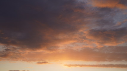Beautiful evening blue sky at sunset with flaming bright light clouds. A warm summer evening at sunset.