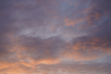 Beautiful evening blue sky at sunset with flaming bright light clouds. A warm summer evening at sunset.