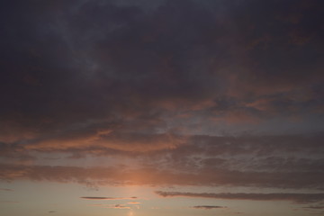 Beautiful evening blue sky at sunset with flaming bright light clouds. A warm summer evening at sunset.