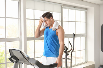 Young man resting after training on treadmill in gym