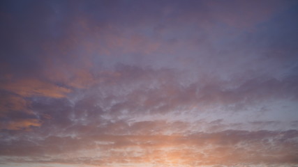 Beautiful evening blue sky at sunset with flaming bright light clouds. A warm summer evening at sunset.