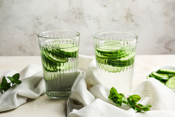 Glasses of infused cucumber water on light background