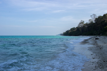 A side angle shot of clean Indian white sandy beach with Indian Ocean and clear blue sky