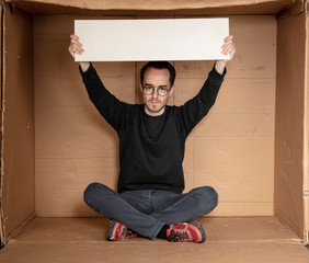 young unemployed man holding a white board, a place for advertising, the idea of a cry for help