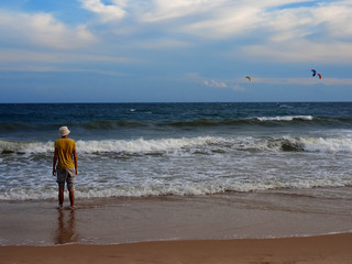 A man stands on the seashore, looks into the distance.       