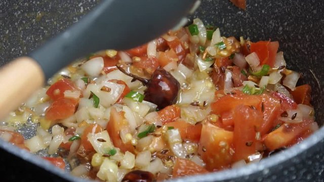 Frying Onions with green chilies, garlic, ginger and cumin seeds to make Tadka to make of spicy Indian lentils called Daal tadka. A 4K video resolution.