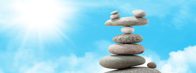 Pyramid of sea pebbles over a sunny sky