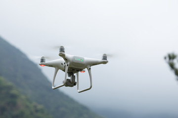 White drone with camera flying in spring mountains