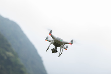 White drone with camera flying in spring mountains