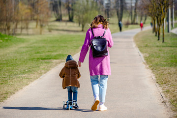 Fototapeta premium A girl with her son walks along a city street in spring 