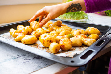 Preparing young potato with spices and herbs to be roasted, baked or grilled. Vegan food. Woman hands