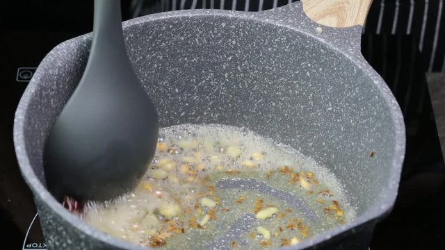 Frying Onions with green chilies, garlic, ginger and cumin seeds to make Tadka to make of spicy Indian lentils called Daal tadka. A 4K video resolution.