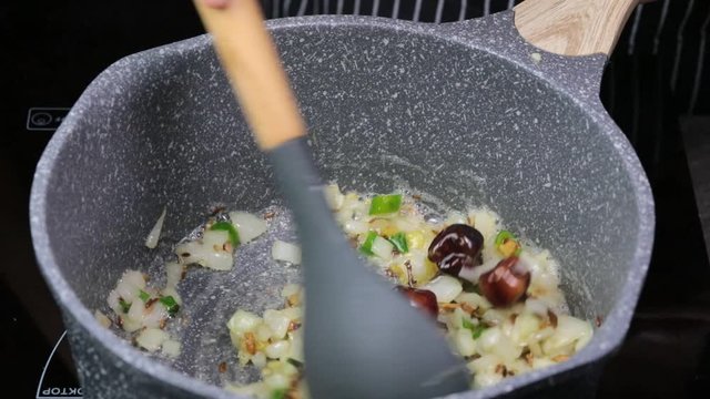 Frying Onions with green chilies, garlic, ginger and cumin seeds to make Tadka to make of spicy Indian lentils called Daal tadka. A 4K video resolution.