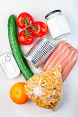 Different food  for donation or delivery at home on a table, in can, glass and plastic bag, vertical, top view