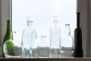 many empty drunk bottles on home window sill on overcast day