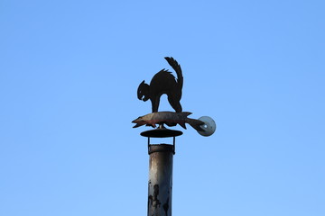 Weather vane on the chimney. Chimney pipe. Cat and Fish silhouette