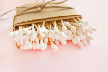 Fototapeta na wymiar Close up of bamboo cotton sticks in paper box bound with flax or hemp cord on pink background. Copy space for your design, zero waste concept