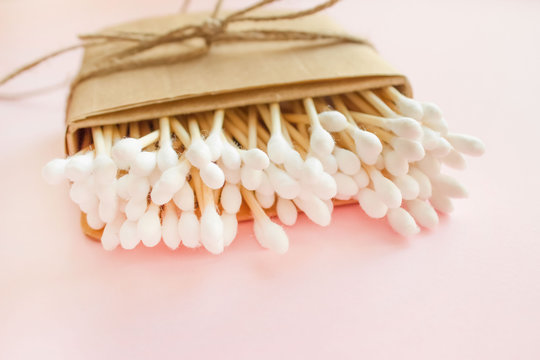 Close up of bamboo cotton sticks in paper box bound with flax or hemp cord on pink background. Copy space for your design, zero waste concept