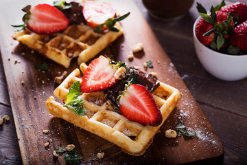 elgian waffles with chocolate sauce and fresh  strawberries on brawn background. Delicious sweet dessert.