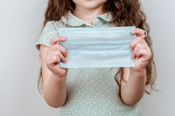 A Girl holds a medical masks in her hands.