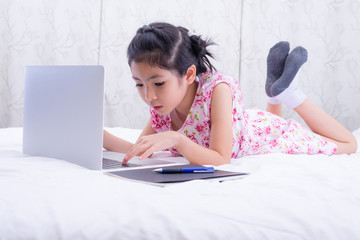 A girl is using a computer in bed to happily study online at home while at home during the period of the outbreak of the covid-19 virus.
