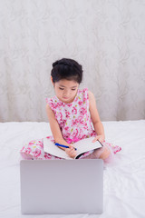 A girl is using a computer in bed to happily study online at home while at home during the period of the outbreak of the covid-19 virus.