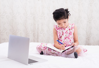 A girl is using a computer in bed to happily study online at home while at home during the period of the outbreak of the covid-19 virus.