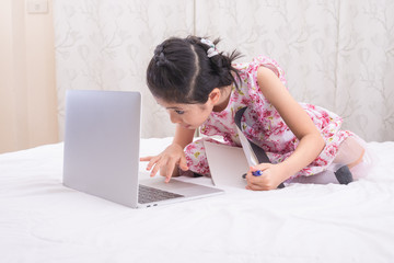 A girl is using a computer in bed to happily study online at home while at home during the period of the outbreak of the covid-19 virus.