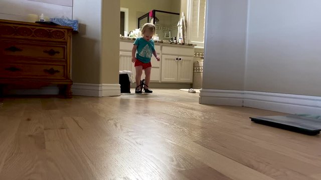 Toddler girl trying on and walking in mother's high heel shoes