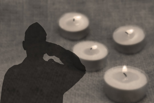Shadow of a soldier Israel Defense Forces, IDF with salutes on grey background with burning funeral candles. Image for Memorial day Yom ha Zikaron or Yom ha Shoah