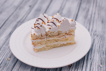 on a white plate a piece of cake with walnut cream on a wooden background