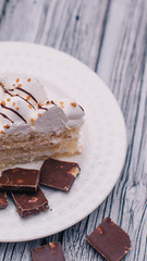 on a white plate chocolate with nuts and a piece of cake with white cream