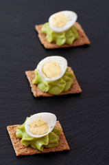 Half of boiled eggs with green mayonnaise on a black tray