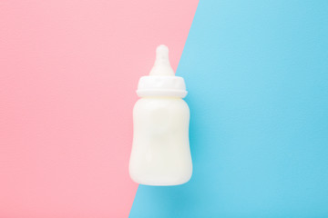 Bottle of white milk on light pink blue table background. Baby feeding concept. Pastel color....